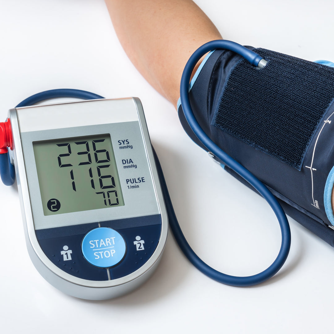 A digital blood pressure monitor displays a high reading of 236/176 mmHg with a pulse rate of 70 beats per minute, while the cuff is wrapped around an arm, indicating active use.