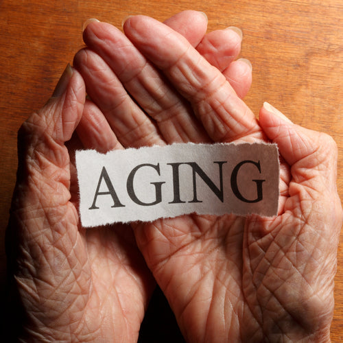 hands holding a piece of paper with the word aging written on it