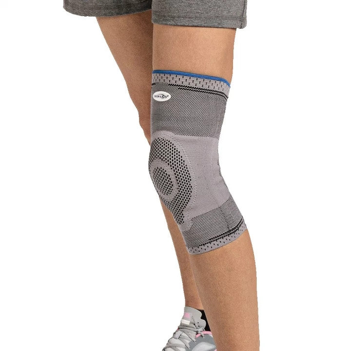 Gray knee brace on a person's leg with a white background